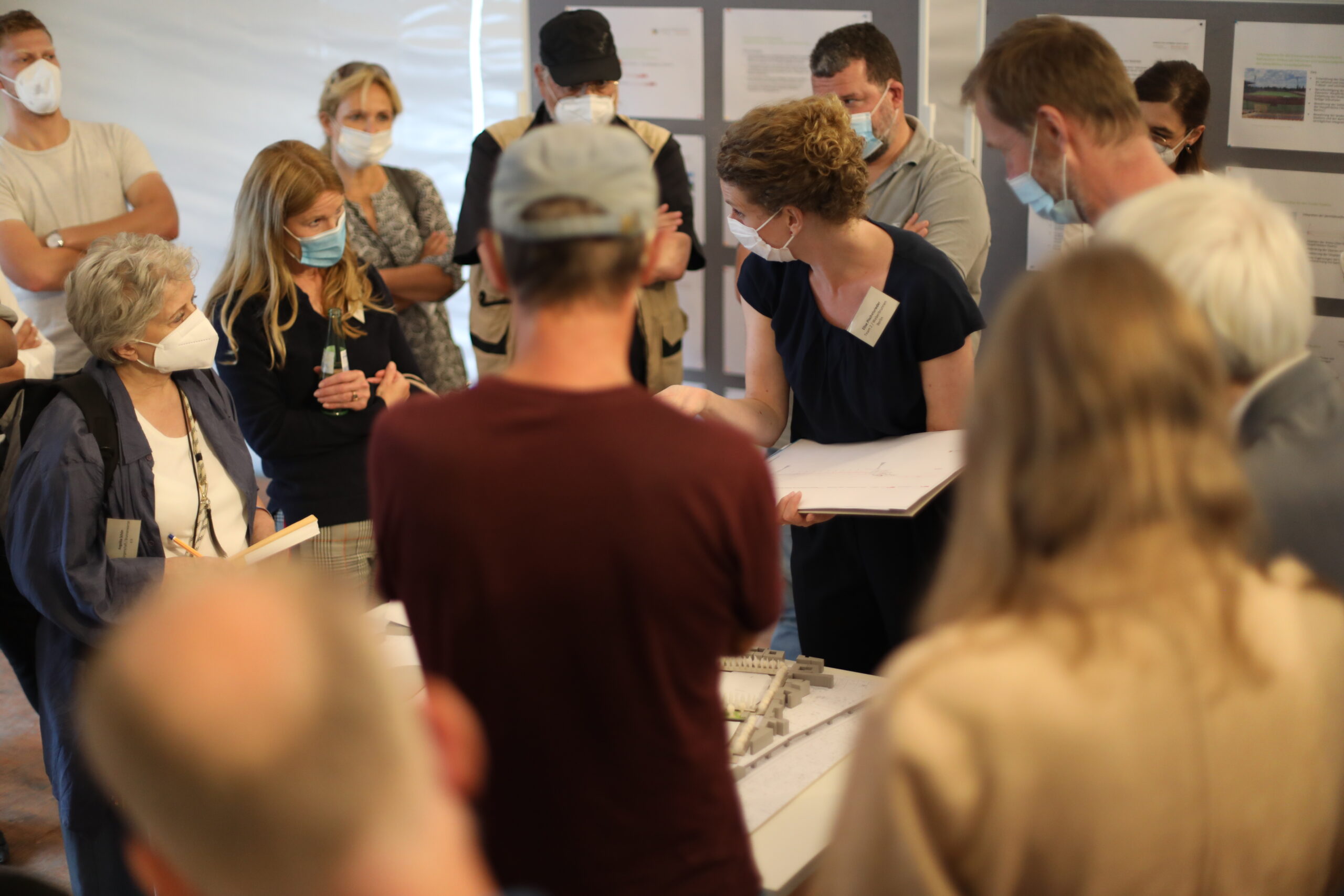 Teilnehmende stehen im Workshopzelt um einen Tisch und diskutieren